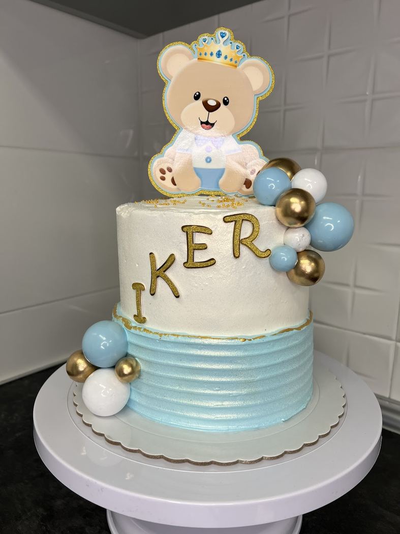 Tarta Iker, decorada con un oso y bolas doradas y azules para un primer cumpleaños.